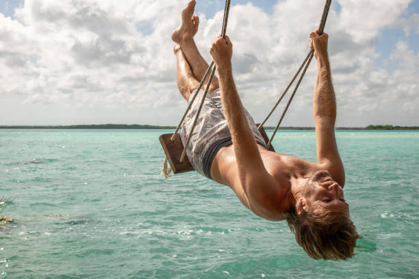 istock Young man having fun on swing in a beautiful lagoon on a sunny day 1430336907