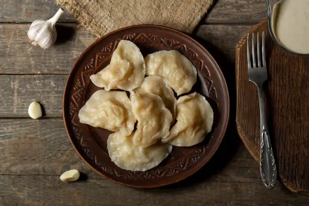 Photo of Traditional Ukrainian dish varenyky with potatoes served in a bowl with sour cream and garlic Ravioli