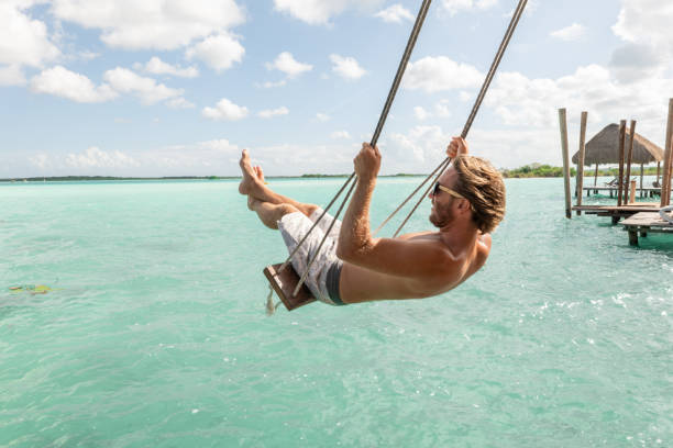 istock Young man having fun on swing in a beautiful lagoon on a sunny day 1430343367