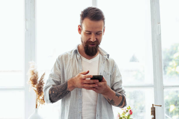 istock Handsome young bearded man spending time at home with phone in hands. 1430344009