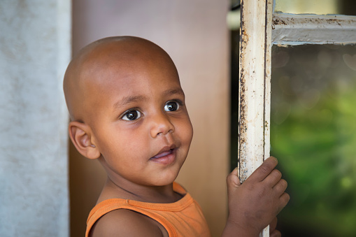 landscape portrait head and shoulders of an African child standing in the frame of an opened glass door