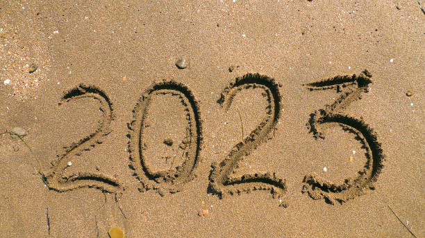 istock 2023 written on sea sand. Sandy textured background. Close-up view. Concept of vacations in a New year. Template for greeting card, postcard, invitation, promotion, websites 1430349607