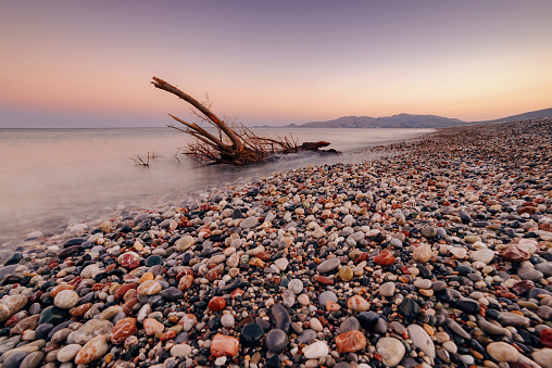 Colorful pebble beach at sunset in Charaki. Charaki (Greek: Χαράκι) is a small fishing village on the east coast of the island of Rhodes, Greece.