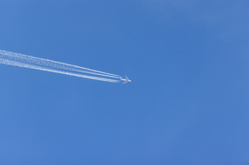 Close-up of a flying commercial aircraft with contrails at high altitude