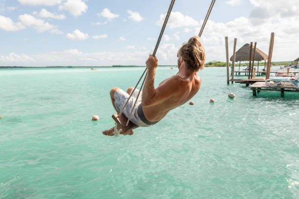 istock Young man having fun on swing in a beautiful lagoon on a sunny day 1430351758