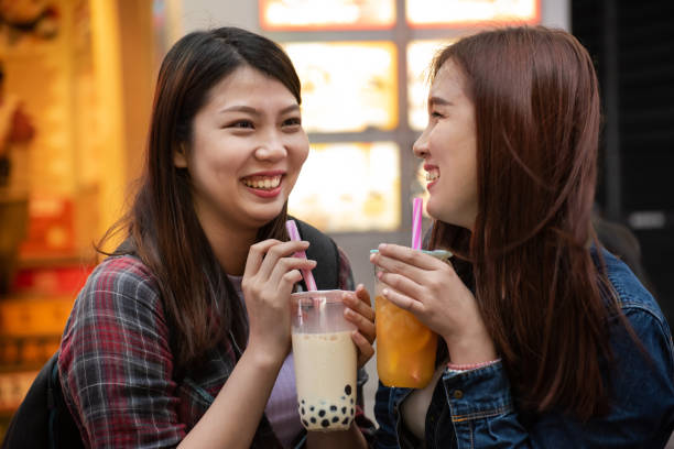 Two joyful Asian women enjoy bubble milk tea together Two young happy Asian women drinking bubble tea and enjoy summer vacation at Xi Meng Ding shopping district, Taipei Taiwan. drinking boba stock pictures, royalty-free photos & images