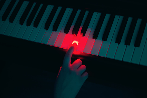 Female hand pressing piano key in the dark