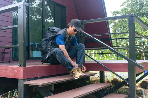 Photo of Tourists carrying backpacks capture the beauty of nature sitting on a hillside wooden terrace.