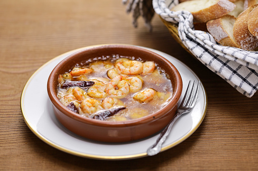 Gambas al Ajillo (A Spanish tapas) ; a cazuela poured with olive oil, minced garlic and chili peppers, shrimps added, cooked and served hot.