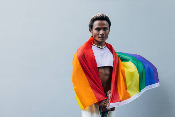 istock Portrait of a young guy with lgbt flag posing outdoors at grey wall 1430360954