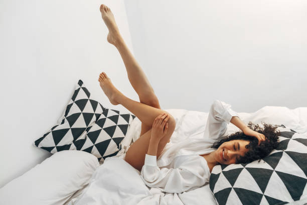 istock Playful young mixed race woman lying on bed with legs up. Copy space. 1430368129