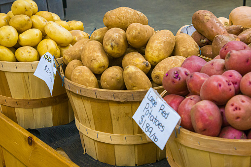 Baskets of Yukon Gold, Idaho, and large red potatoes, labeled, priced and ready for sale at a farm stand in central Massachusetts.