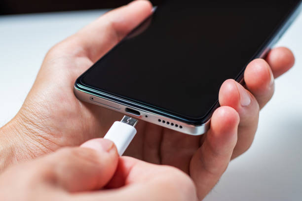 istock Charging a smartphone via a USB cable and a power supply. A black smartphone hanging with a usb charging cable. 1430371394