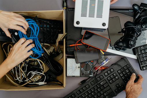 Image of asian people putting old computer parts, smartphone and cables for into cardboard box for recycling. Asian people recycling electronic waste.