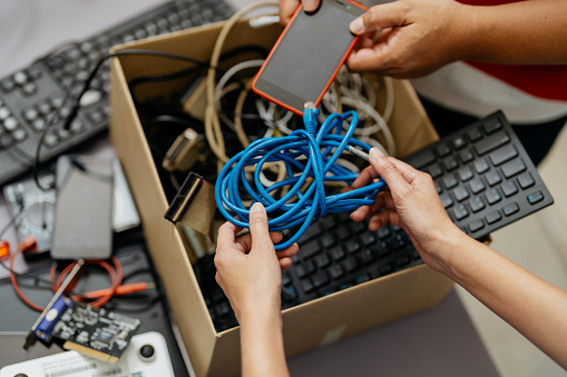 Image of asian people putting old computer parts, smartphone and cables for into cardboard box for recycling. Asian people recycling electronic waste.