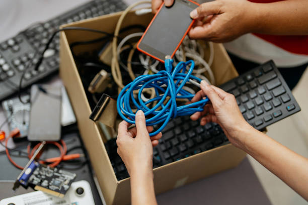 Recycling electronic waste Image of asian people putting old computer parts, smartphone and cables for into cardboard box for recycling. Asian people recycling electronic waste. computer equipment box stock pictures, royalty-free photos & images