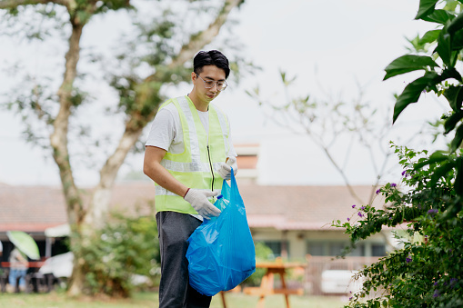 Image of an Asian Chinese man picking up plastic waste and rubbish in public park