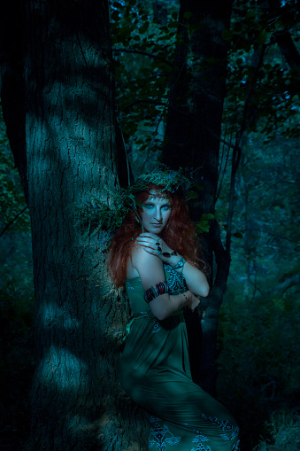 Redhead beautiful lady in green dress posing in the forest