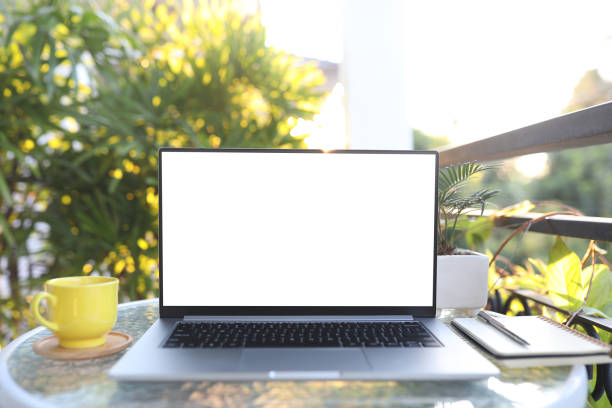 istock Laptop front view and yellow coffee cup with notebooks on white glass table outdoor balcony 1430376102