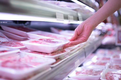 Woman's hand holding a pack of meat