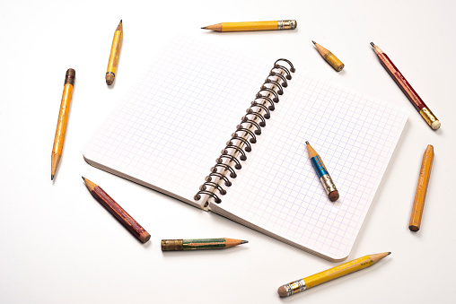 High angle view of notebook with pencils on white table