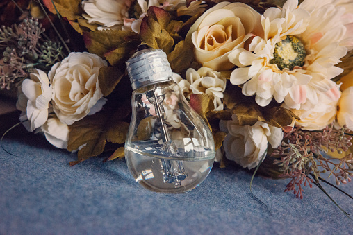 Lightbulb filled with water leaning against vintage flower bouquet