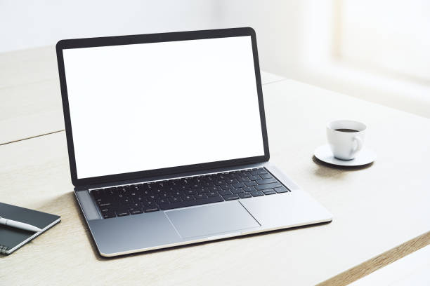 istock Perspective view on blank white modern laptop monitor with copyspace for your logo or text on light wooden table with coffee mug in sunny office area. 3D rendering, mock up 1430388193