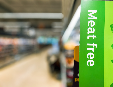 Sign in a supermarket aisle with the words 'meet free'. Focus on the sign with the supermarket shelves defocused beyond.