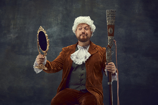 Portrait of the senior male magician, wearing a tail coat and cylinder while performing magic tricks on the stage at the theatre