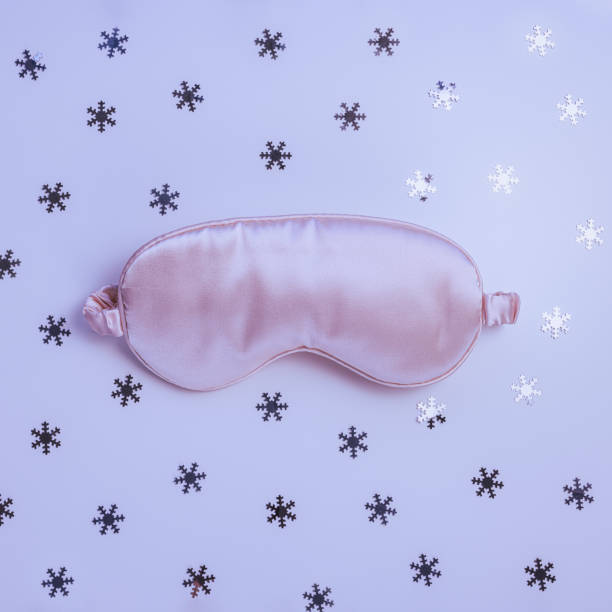 istock Pink satin eye sleeping mask on winter background with snowflakes 1430397825