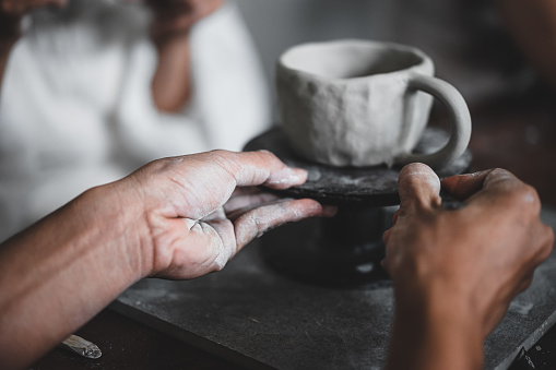 Selective focus. View of male hands works with clay makes future ceramic plate, ceramic artist makes classes of hand building in modern pottery workshop, creative people handcrafted design