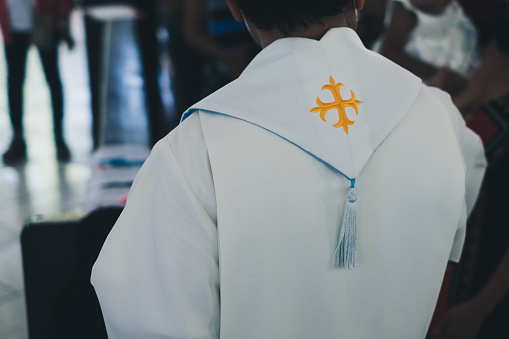 Giant gold cross set embroidery at the back of the stole worn by Christian priest. Selected focus.