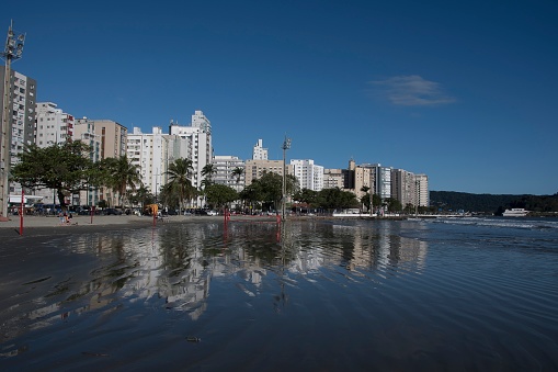 Santos, Brazil. Waterfront buildings reflected in the sea water of the beach. Ponta da Praia region.