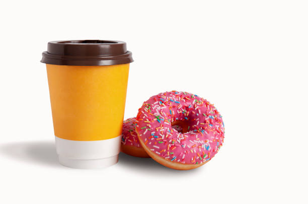 blank yellow takeaway cup of coffee with a brown lid. glazed donut with pink icing with sprinkles nearby - starbucks take out food coffee disposable cup imagens e fotografias de stock