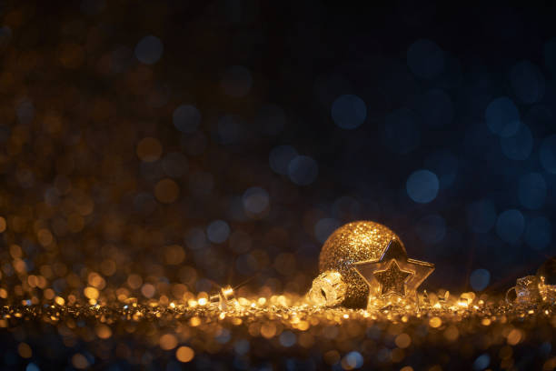 Shiny Christmas decoration on gold and blue defocused lights - holiday background star bokeh Still life photography of an abstract holiday / party  background. Shiny Christmas decoration on gold and blue defocused lights. Golden shiny glitter, lens flares, and defocused blue lights. Native image size: 7952x5304 christmas star shape christmas lights blue stock pictures, royalty-free photos & images