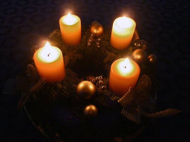 Advent wreath with four glowing candles and golden decoration in the dark