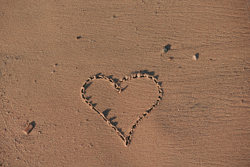 Romantic Valentine’s Day love heart handwritten in textured sand