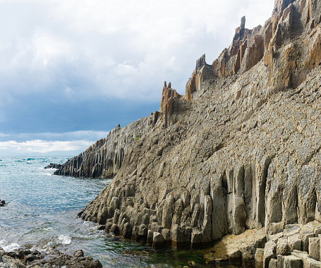 ocean shore with rocks of columnar basalt, Cape Stolbchaty on Kunashir Island