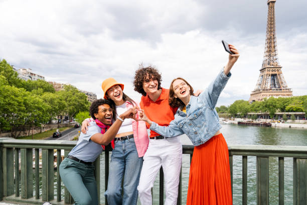 groupe de jeunes amis heureux en visite à paris et à la tour eiffel - mobile phone group of people photographing teenager photos et images de collection