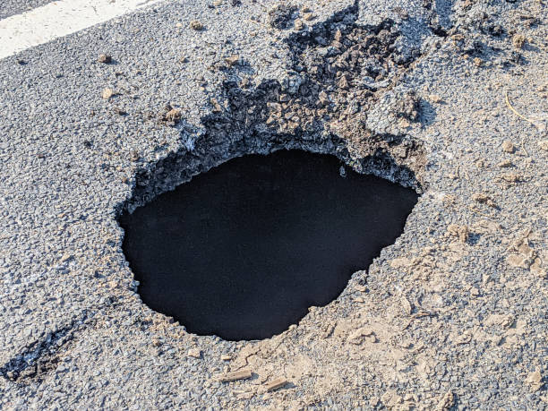 istock Deep sink hole opened up in a tarmac road surface. 1430418980