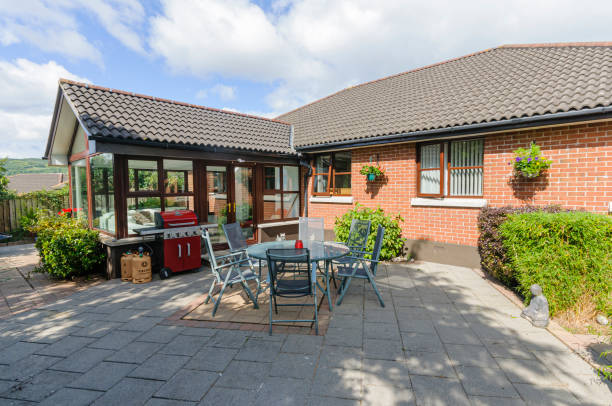 istock Modern patio with a table, chairs and barbeque behind a bungalow and sunroom. 1430421038