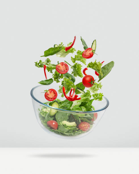 Lettuce falling into a glass salad bowl. Healthy food, diet. Levitating salad. Lettuce falling into a glass salad bowl. Healthy food, diet. Levitating salad. arugula falling stock pictures, royalty-free photos & images