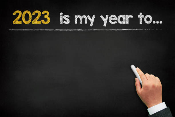 2023 new year expectations. A male hand writing new year resolution planning on chalkboard stock photo