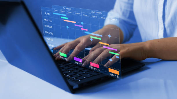 istock Business Project Management System. Project manager working on laptop and updating tasks and milestones progress planning with Gantt chart scheduling interface for company on virtual screen. 1430431120