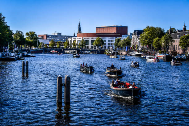 le canal de la rivière amstel regorge de bateaux à amsterdam, aux pays-bas - montelbaan tower photos et images de collection