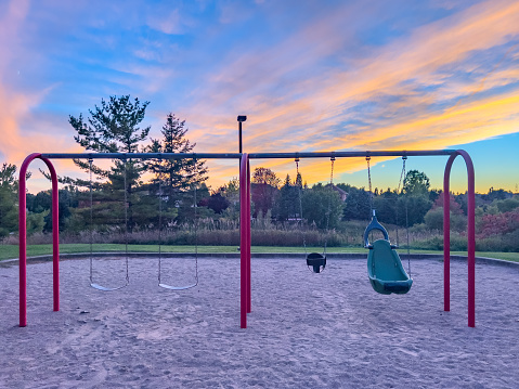 Empty modern outdoor playground in summer. A beautiful place for children's games, sports and recreation with benches, swings and slides. Safe rubber floor covering for baby's health
