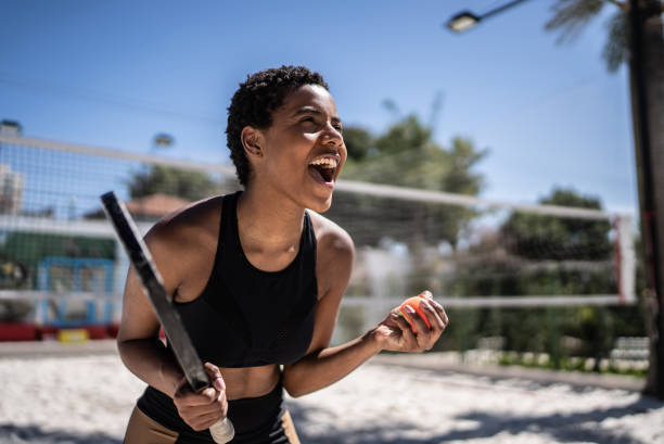 une femme excitée célébrant pendant un match de tennis de plage - tennis women one person vitality photos et images de collection