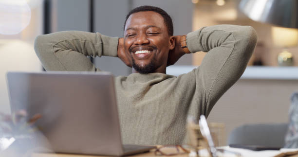 istock Man with his laptop, taking a rest and relax after doing work in his home. Black man, smiling and happy person being done with a task on his computer. Stress free, relaxing and working online 1430437804