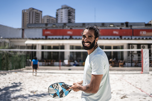 Portrait of a young man playing beach tennis