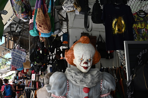 Heraklion, Greece - 22 09 2022: Detail of Pennywise, the Dancing Clown, exhibited as advertisement in one stall with cloth and dresses in the market place in commercial and merchant district of town.